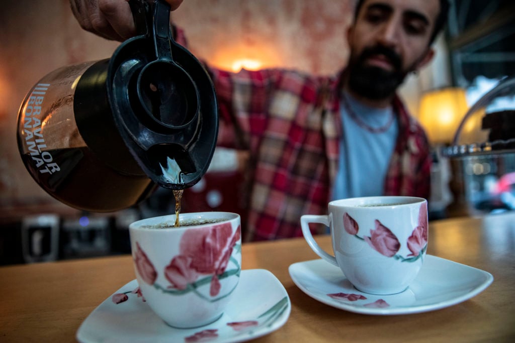 A man seen serving the prepared filtered coffee into cups