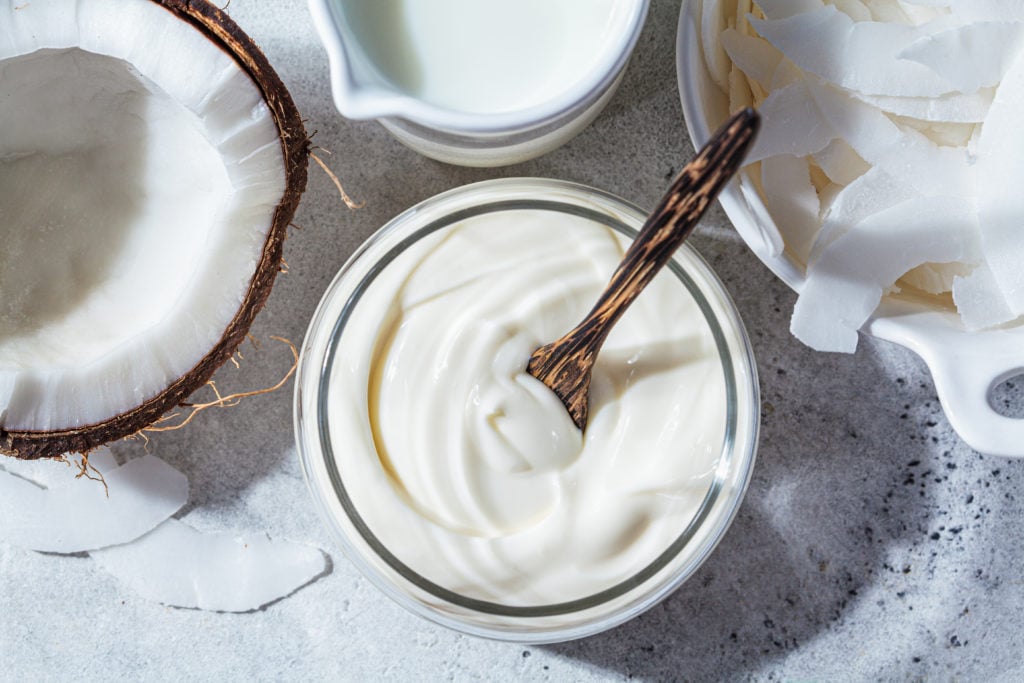 Vegan coconut products - milk, yogurt and chips, white background, top view. Coconut food concept.