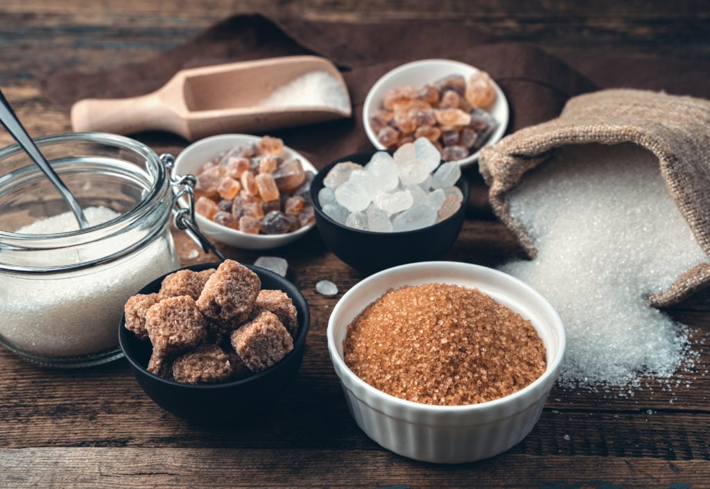 Many different types of sugar on a wooden background. Side view